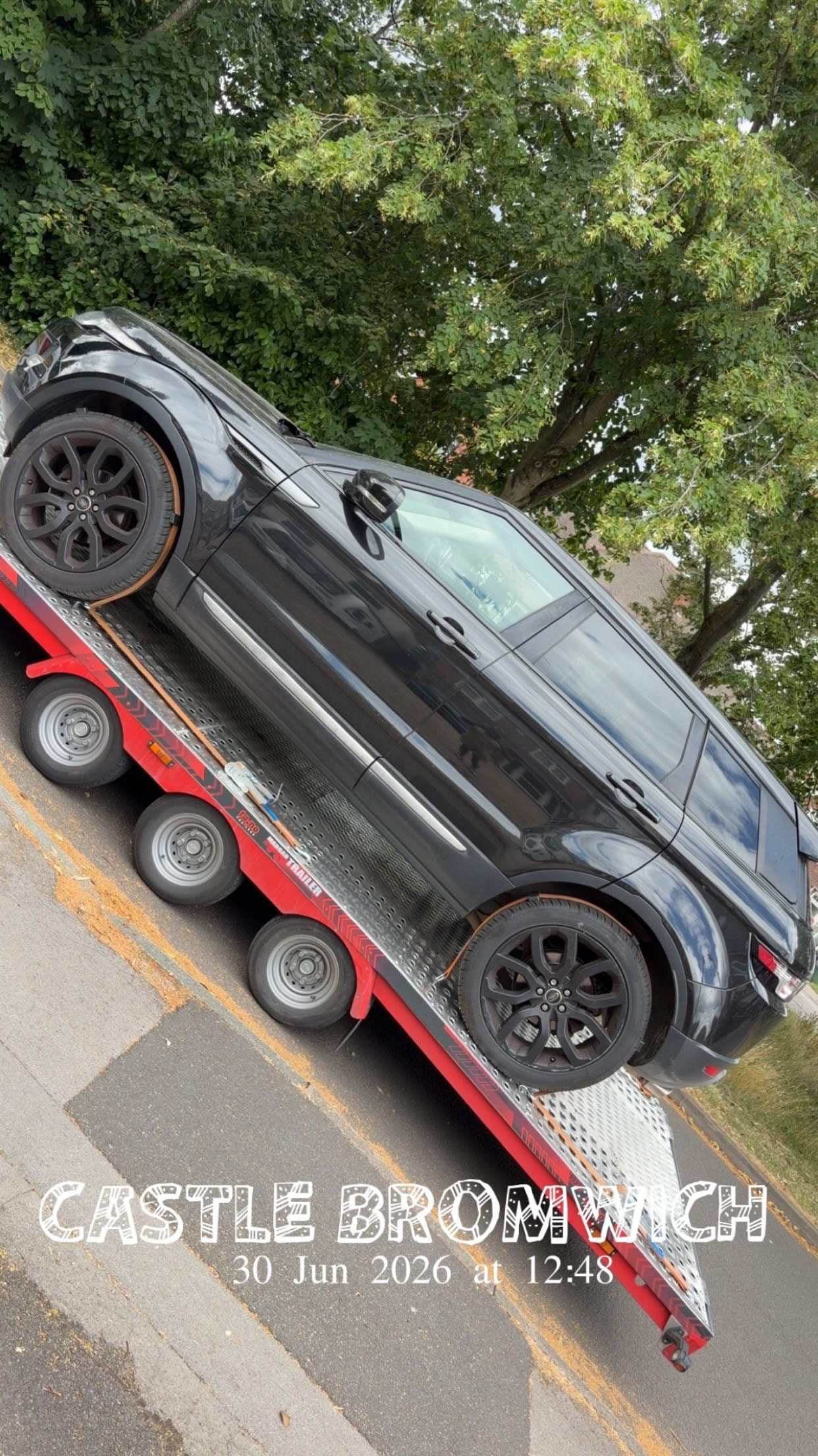 Range Rover loaded on red flatbed transporter — Castle Bromwich job